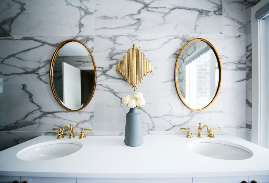 Bright marble and gold bathroom with two sinks and two mirrors in a bathroom