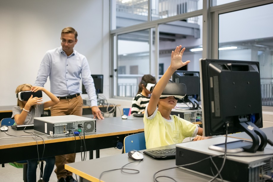 Group of multiethnic kids wearing VR headsets and teacher watching them